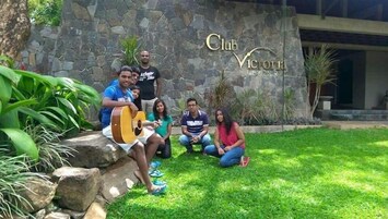 Un grupo de personas en un patio con un muro de piedra y un letrero que dice 'Club Victoria'.
