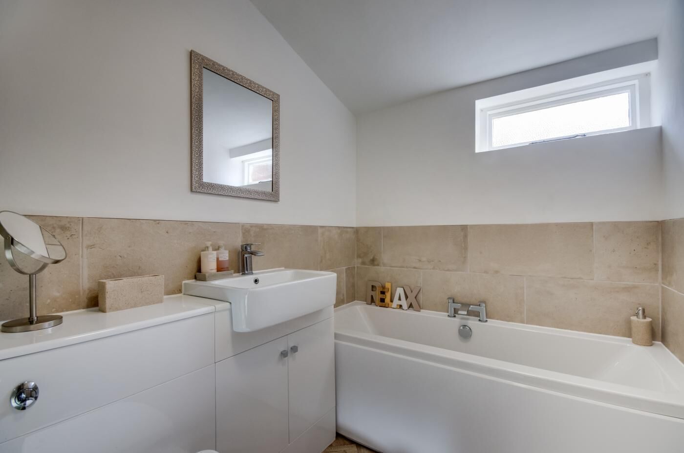 A bathroom with a sink, mirror, and bathtub.