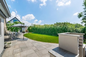 A patio area with a table and chairs, a covered seating area, and a well-maintained lawn. - 5 Bed in Little Petherick (oc-p00736) (Tregonna)