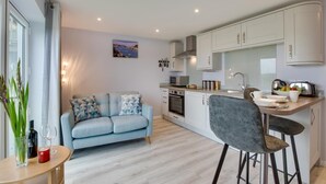 Eine moderne Wohnung mit Küchenzeile, einer Couch, einem Essbereich und Blick auf die Stadt.