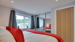 Ein Hotelzimmer mit einem großen Bett, einer Holztür und einem Fenster mit Vorhängen.