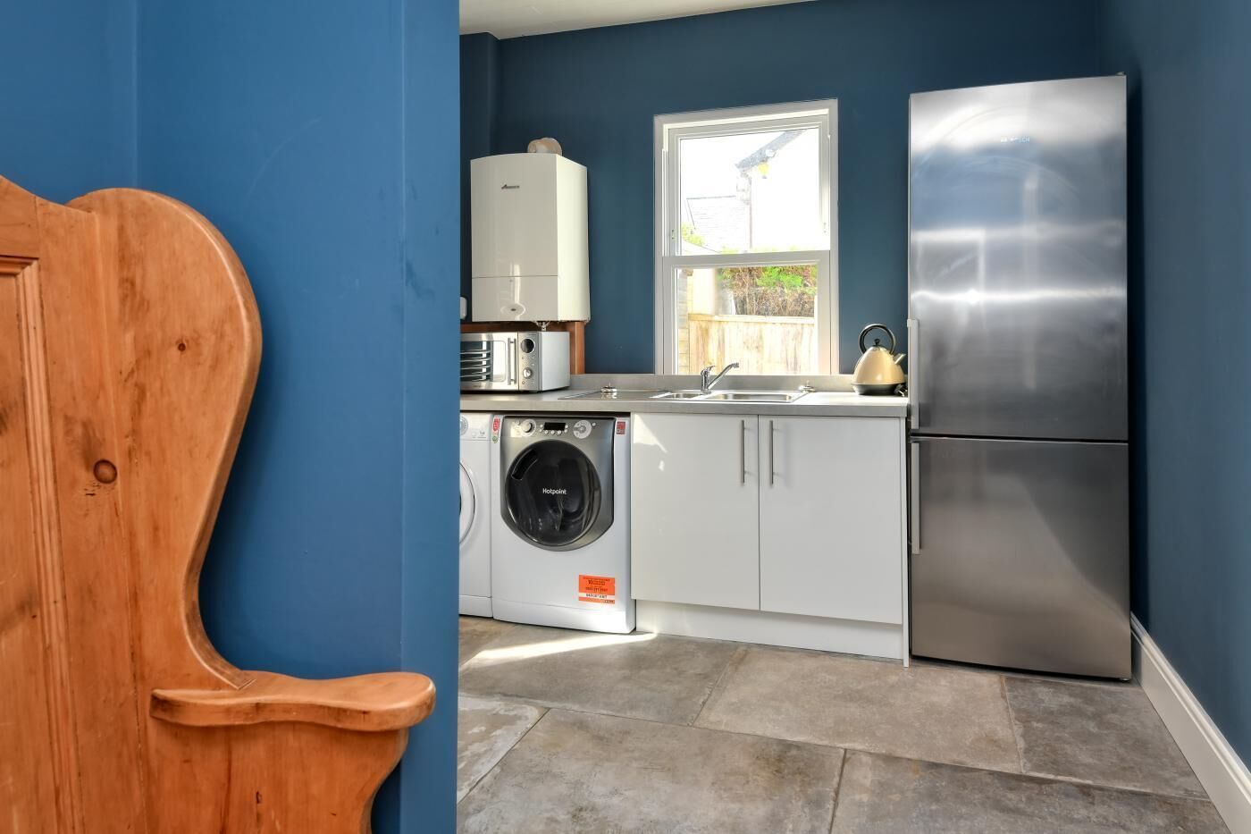 A modern kitchen with a stainless steel refrigerator, a washing machine, and a microwave.