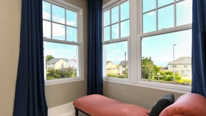 A room with a bench and a view of houses through large windows.