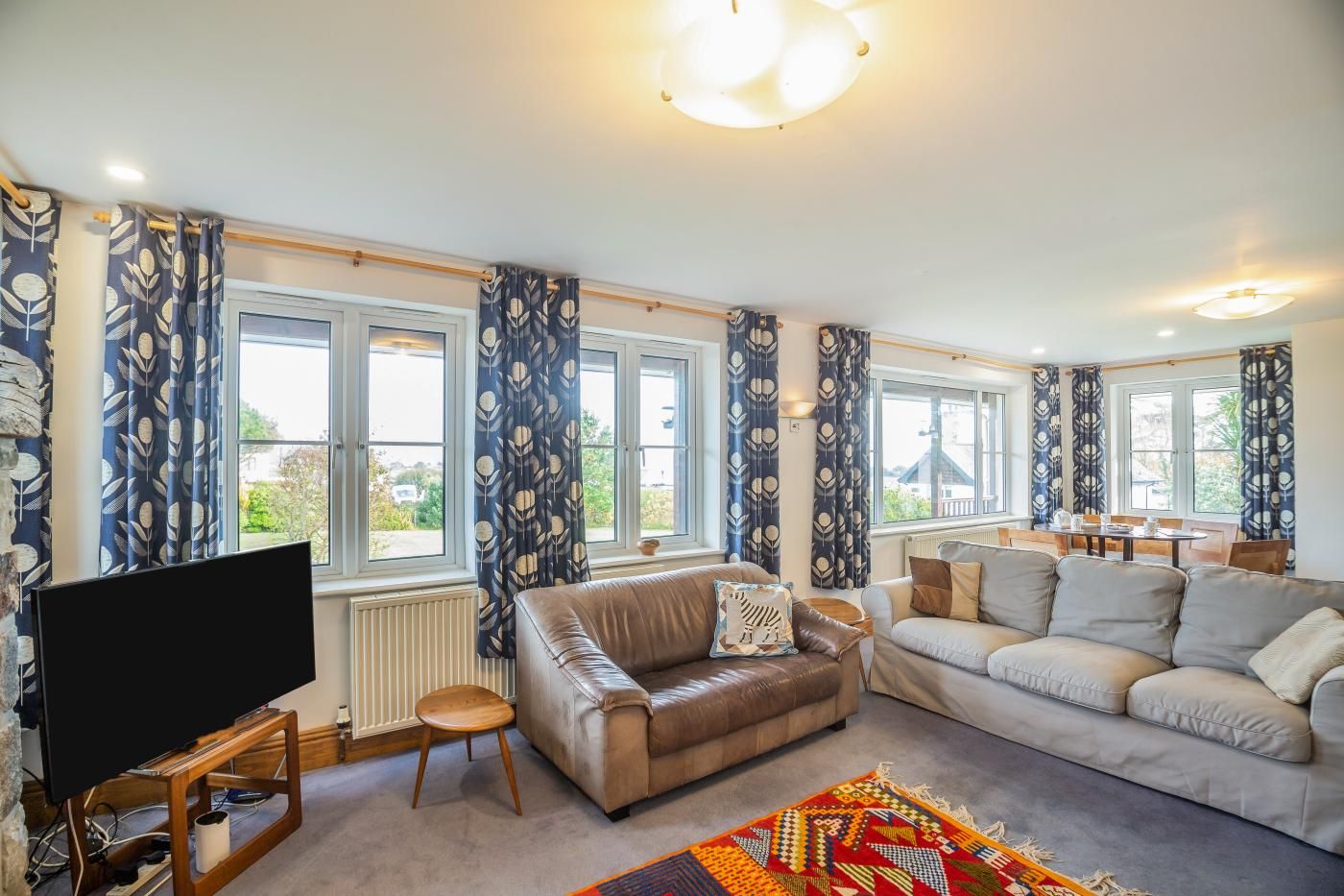 A living room with two sofas, a TV, and a patterned rug.