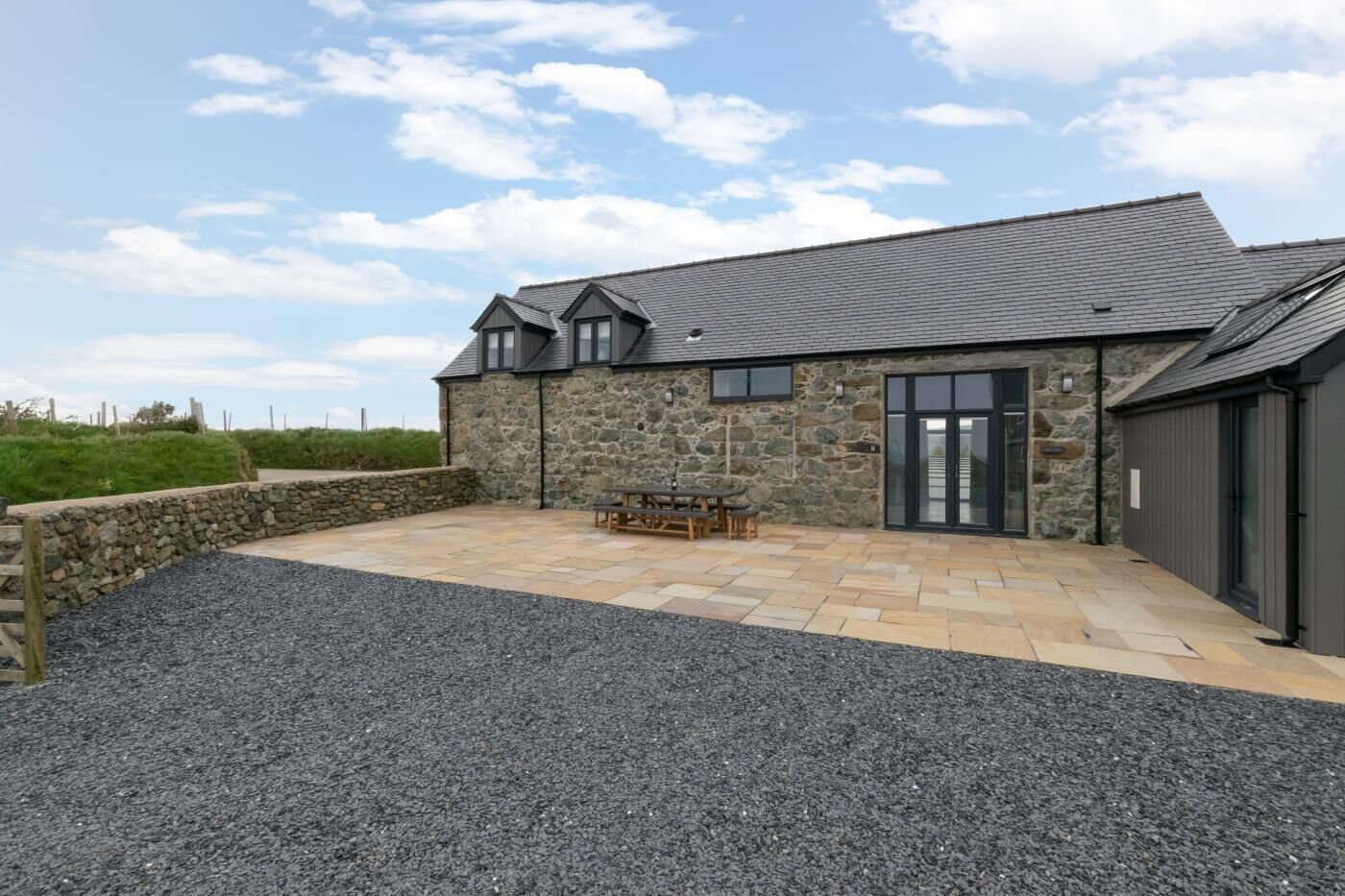 A stone building with a patio area, a table, and chairs.