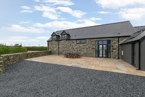 A stone building with a patio area, a table, and chairs. - 2 Bed in Aberdaron (oc-bow86) (Rhoshirwaun)