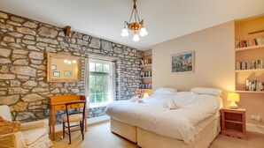 A bedroom with a stone wall, a bed, a desk, and a bookshelf. - 5 Bed in Llanmadoc (oc-hh2111) (Llanmadoc)