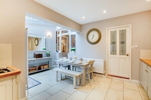 Een moderne keuken met witte kastjes, een eettafel gedekt voor vier personen en een grote wandklok.