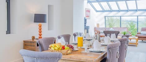 Un comedor moderno con una mesa de madera dispuesta para el desayuno, incluyendo frutas y jugo.