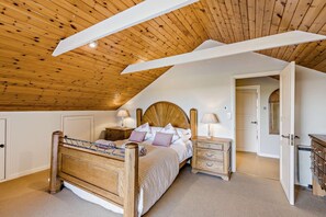 Ein Schlafzimmer mit Holzboden, einem Bett mit Kopfteil, Nachttischen und einem Kleiderschrank.