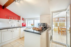 Eine moderne Küche mit weißen Schränken, einer roten Akzentwand und einem Essbereich mit Blick.