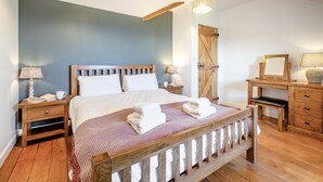 Um quarto com cama de madeira, mesas de cabeceira, cômoda e espelho.