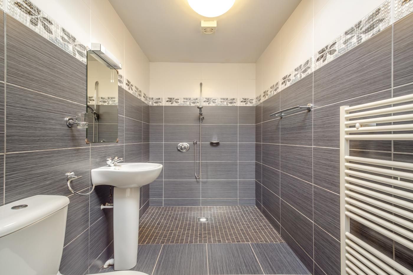 Une salle de bain comprenant des toilettes, un lavabo, une douche et un porte-serviettes.