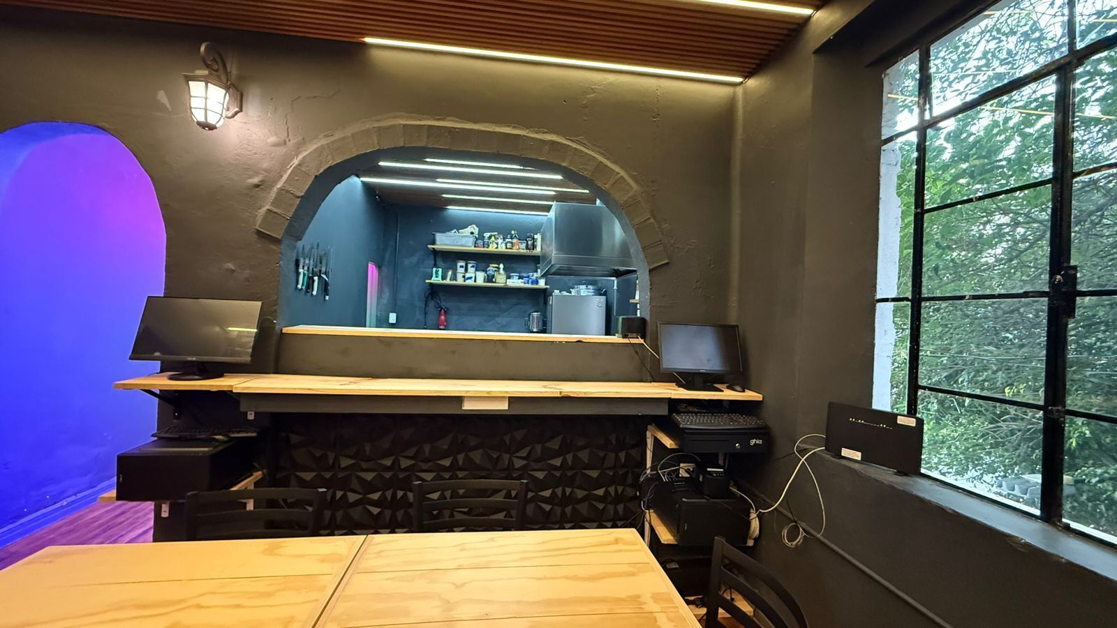 Une cuisine moderne avec une arche en pierre, un comptoir en bois et deux écrans d’ordinateur.