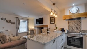 A modern kitchen with a marble countertop, built-in oven, and a clock on the wall. - 1 Bed in Conwy (oc-bow118) (Conwy)
