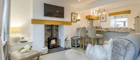 A living room with a fireplace, a television, and a bar area with stools.