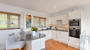Een moderne keuken met witte kastjes, een granieten aanrecht en roestvrijstalen apparatuur.