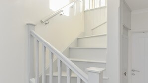 Een witte trap met een leuning, die leidt naar een plateau en een deur.