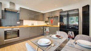 Een moderne keuken met grijze kastjes, een houten aanrechtblad en een eethoek voor twee personen, gedekt voor een maaltijd.