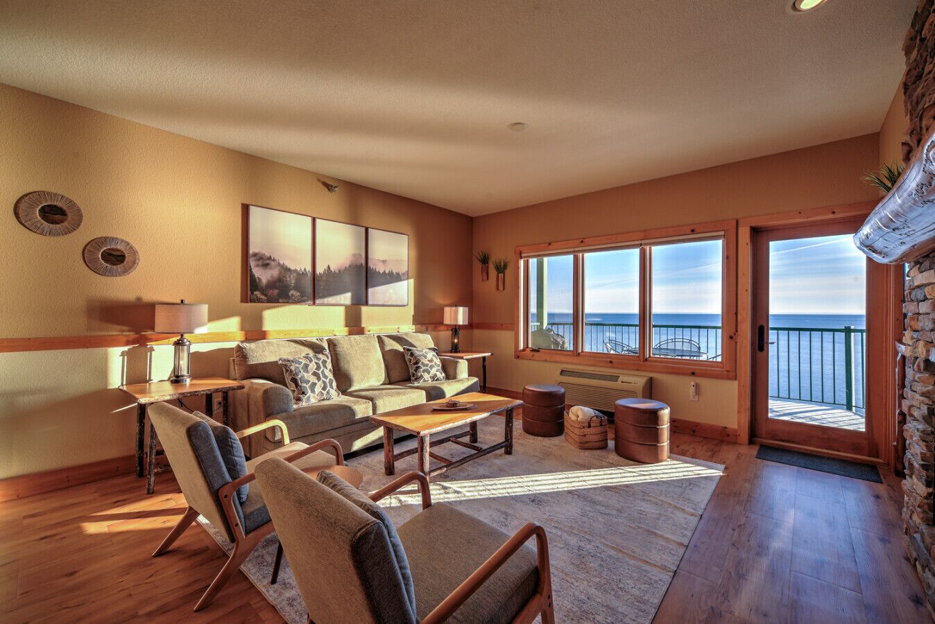 Ein gemütliches Wohnzimmer mit einer Couch, Sesseln, einem Couchtisch und einem großen Fenster mit Blick auf den Ozean.