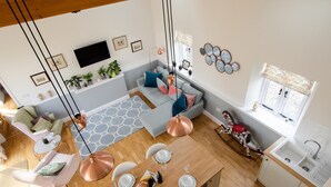 A modern living room with a sofa, dining table, and kitchen area.