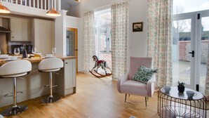 A spacious living area with a kitchen, dining area, and a balcony with a rocking horse.