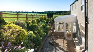 Une maison avec un jardin, une clôture en bois et une vue dégagée sur la campagne environnante.