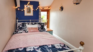 A bedroom with a bed, floral bedding, a pink quilt, and a wall-mounted picture. - 2 Bed in Nefyn (oc-tynixs) (Nefyn)
