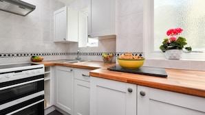 A compact kitchen with white cabinetry, a black oven, and a wooden countertop. - 2 Bed in Nefyn (oc-tynixs) (Nefyn)