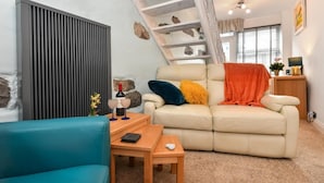 A cozy living room with a sofa, a blue armchair, and a wooden coffee table. - 2 Bed in Nefyn (oc-tynixs) (Nefyn)