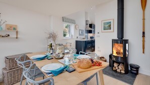 Een moderne keuken met een houtkachel, een eettafel voor vier personen, en uitzicht op de omgeving.