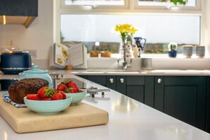 A kitchen counter with a loaf of bread, a bowl of strawberries, and a teapot. - 2 Bed in Polruan (oc-p00896) (England)