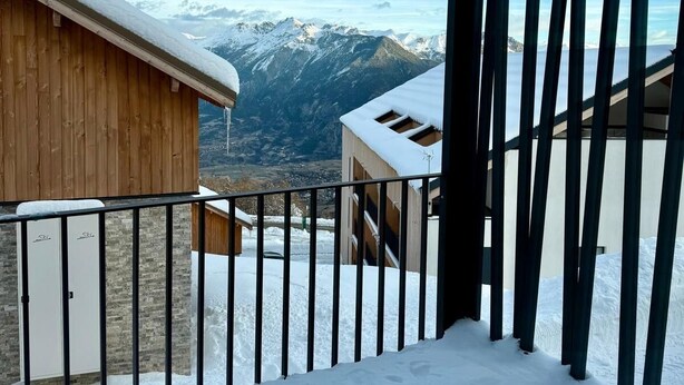 Un balcon enneigé avec vue sur les montagnes.