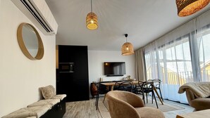 Un salon moderne comprenant un canapé, des fauteuils, une table à manger et un téléviseur.