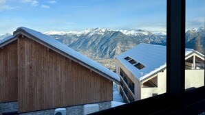 Un bâtiment en bois avec un toit en pente, une vue sur des montagnes enneigées et un ciel dégagé.