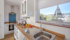 Eine moderne Küche mit Holzarbeitsplatte, Spüle aus Edelstahl und Blick auf ein Segelboot durch ein Fenster.
