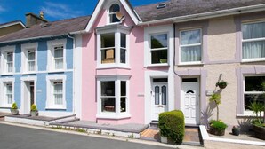 A row of colorful houses with distinct architectural styles, including a pink house with a bay window and a blue house with white trim. - 4 Bed in New Quay (oc-bow272) (New Quay)
