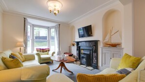 A cozy living room with a fireplace, comfortable seating, and a television. - 4 Bed in New Quay (oc-bow272) (New Quay)