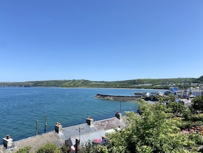 En kystby med frit udsyn til havet, en moler af sten og frodig vegetation.