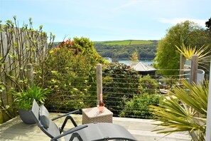 A patio with a view of a lake and hills, featuring a wicker chair, a small table, and a potted plant. - 3 Bed in Fowey (oc-tidewa) (Fowey)