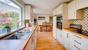 Een moderne keuken met een groot raam, houten vloeren en een eethoek met een tafel en stoelen.