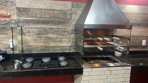 Een professionele keuken met roestvrijstalen apparatuur, een tegelwand van baksteen en een metalen afzuigkap.