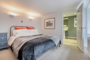 A bedroom with a bed, bedside table, and a door leading to a bathroom. - 2 Bed in Beer (oc-jbchur) (Beer)