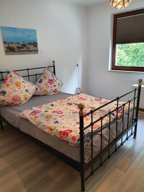 A bed with a floral bedspread, a black metal frame, and two decorative pillows.