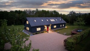 Une maison moderne à deux étages, dotée d’un toit en pente, d’une allée et d’une pelouse bien entretenue.