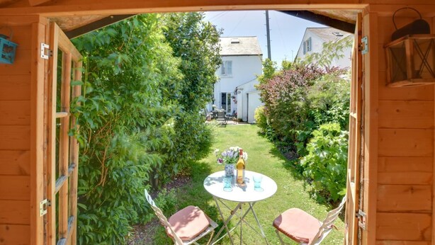A wooden structure with a garden view, a small table with chairs, and a bottle of wine. - 2 Bed in Deal (oc-cc0163) (Kingsdown)