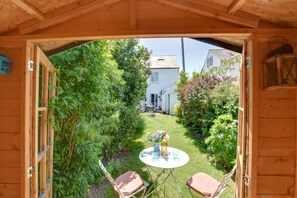 A wooden structure with a garden view, a small table with chairs, and a bottle of wine. - 2 Bed in Deal (oc-cc0163) (Kingsdown)
