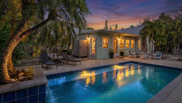 A poolside area with a house, lounge chairs, and a palm tree. - Rustic Coastal Escape| Pool | Fire Pit (Bradenton)