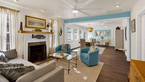 A spacious living room with a fireplace, a ceiling fan, and a dining area in the background. - Rustic Coastal Escape| Pool | Fire Pit (Bradenton)