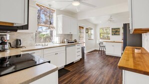 A modern kitchen with white cabinets, a wooden countertop, and a ceiling fan. - Rustic Coastal Escape| Pool | Fire Pit (Bradenton)